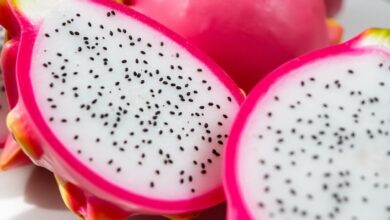 فوائد فاكهة التنين الطازجة، مقطعة ونصفين، مع بذورها السوداء.